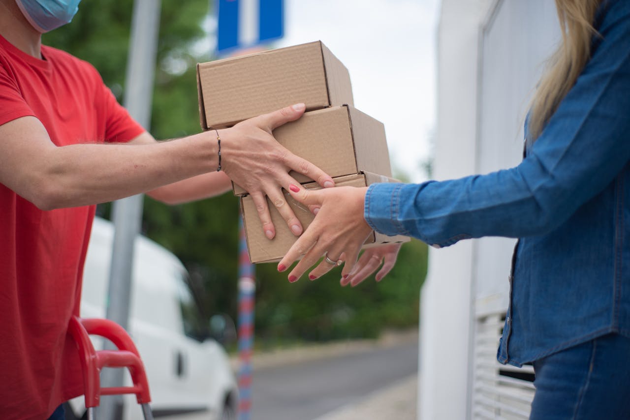 client-stories-img Hands exchanging cardboard boxes during an outdoor delivery scene.